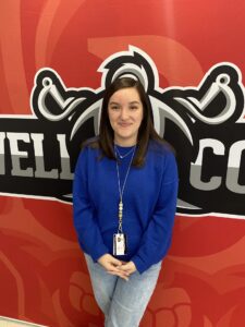 Young woman standing in front of school logo