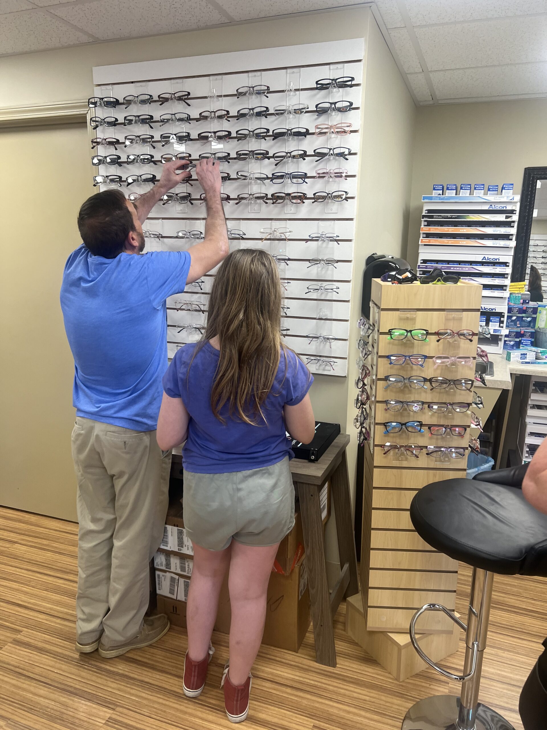 An adult helps a student pick out frames for their new glasses