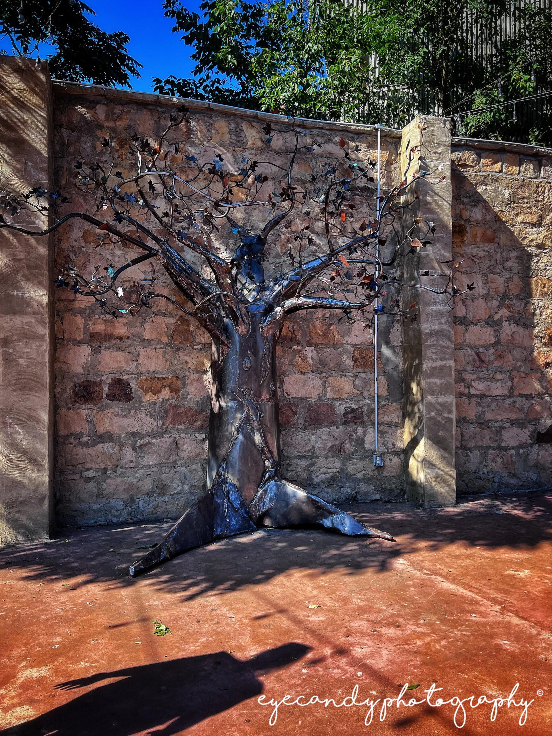 sculpture of a tree against a brick wall