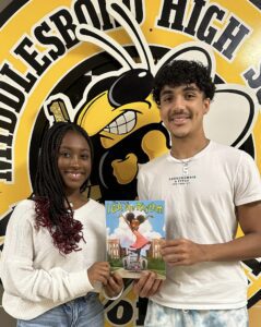 Two teenage students holding a copy of a children's book titled I Got Rythm